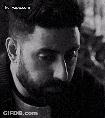 A Man With A Beard Is Looking Down In A Black And White Photo . GIF