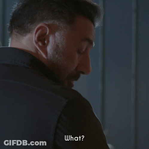 A Man With A Beard Is Looking Over His Shoulder And Says " What " GIF