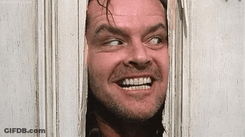 A Man With A Beard Is Looking Through A Door And Smiling . GIF