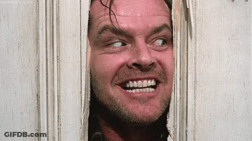 A Man With A Beard Is Looking Through A Hole In A Door And Smiling . GIF