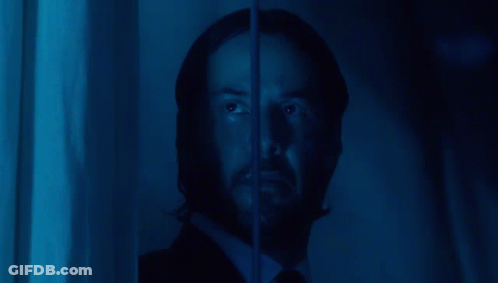 A Man With A Beard Is Looking Through A Window With A Blue Light Behind Him GIF