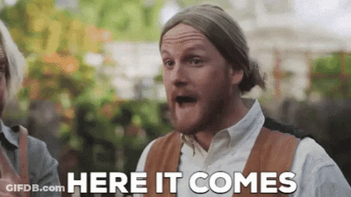 A Man With A Beard Is Making A Funny Face And Says Here It Comes GIF