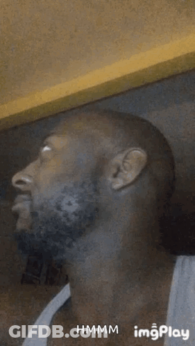 A Man With A Beard Is Making A Funny Face In A White Tank Top . GIF