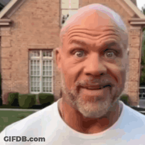 A Man With A Beard Is Making A Funny Face In Front Of A Brick House GIF