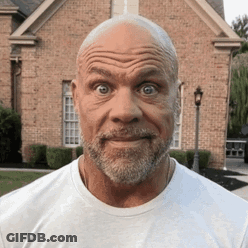 A Man With A Beard Is Making A Funny Face In Front Of A Brick House GIF