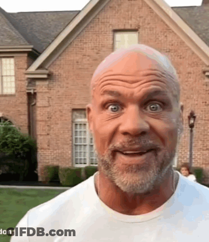 A Man With A Beard Is Making A Funny Face In Front Of A Brick House . GIF