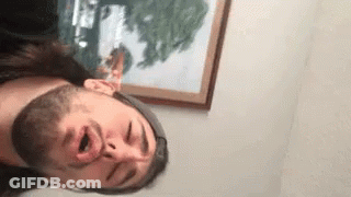 A Man With A Beard Is Making A Funny Face In Front Of A Painting . GIF
