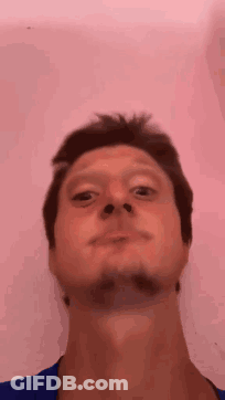 A Man With A Beard Is Making A Funny Face In Front Of A Pink Background . GIF