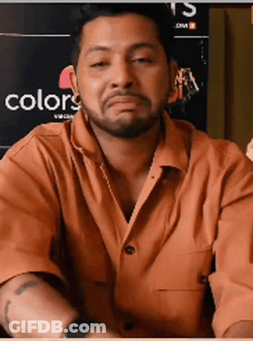 A Man With A Beard Is Making A Funny Face In Front Of A Poster That Says Colors GIF
