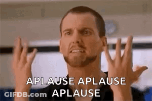 A Man With A Beard Is Making A Funny Face While Applauding . GIF