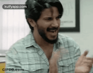 A Man With A Beard Is Making A Funny Face While Clapping His Hands . GIF