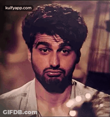 A Man With A Beard Is Making A Funny Face While Looking At The Camera . GIF