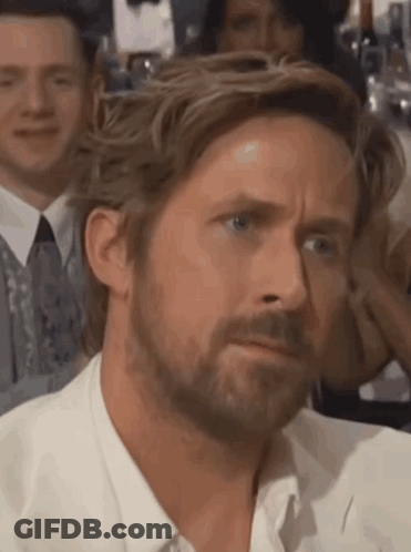 A Man With A Beard Is Making A Funny Face While Sitting In A Crowd . GIF