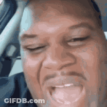 A Man With A Beard Is Making A Funny Face While Sitting In The Driver 'S Seat Of A Car . GIF