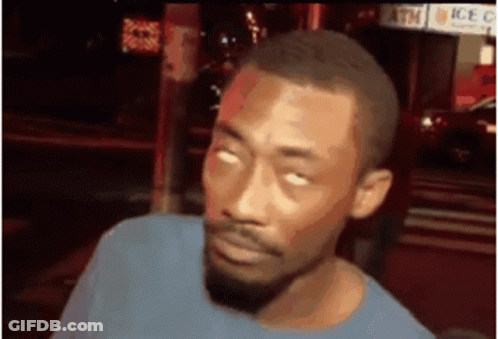 A Man With A Beard Is Making A Funny Face While Standing In Front Of A Sign That Says Atm . GIF
