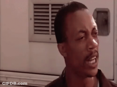 A Man With A Beard Is Making A Funny Face While Standing In Front Of A White Truck . GIF