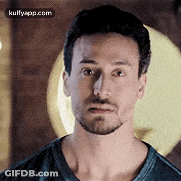 A Man With A Beard Is Making A Funny Face While Wearing A Black Shirt . GIF