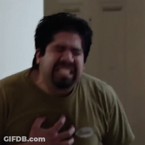 A Man With A Beard Is Making A Funny Face While Wearing A Green Shirt GIF