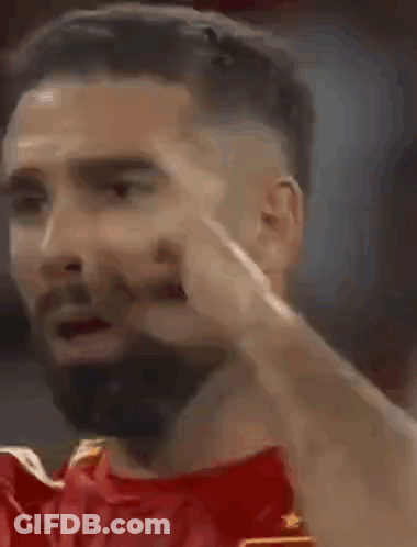 A Man With A Beard Is Making A Funny Face While Wearing A Red Shirt . GIF