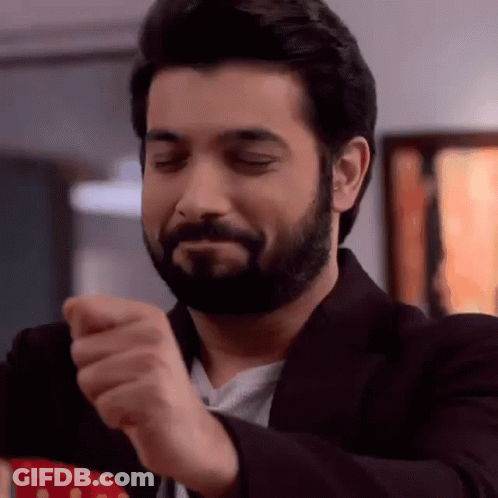 A Man With A Beard Is Making A Funny Face While Wearing A Suit And A Tie . GIF