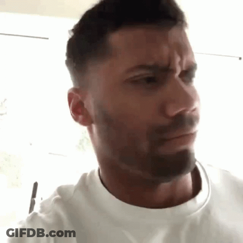 A Man With A Beard Is Making A Funny Face While Wearing A White T-Shirt . GIF