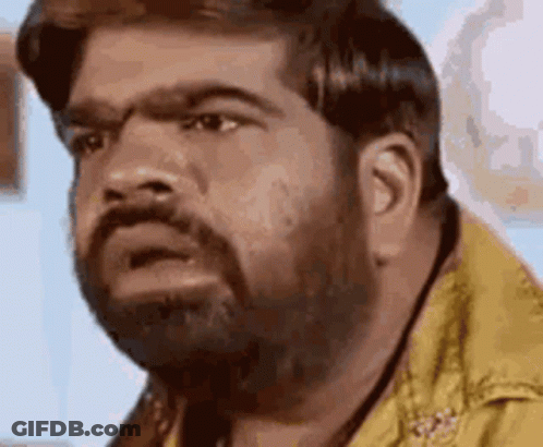 A Man With A Beard Is Making A Funny Face While Wearing A Yellow Shirt . GIF