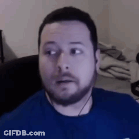 A Man With A Beard Is Making A Funny Face While Wearing Headphones And A Blue Shirt . GIF