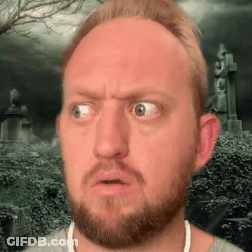 A Man With A Beard Is Making A Funny Face With A Cemetery In The Background GIF