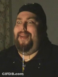 A Man With A Beard Is Making A Funny Face With A Stream Of Liquid Coming Out Of His Mouth GIF