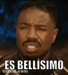 A Man With A Beard Is Making A Funny Face With The Words `` Es Bellissimo '' Written On It . GIF