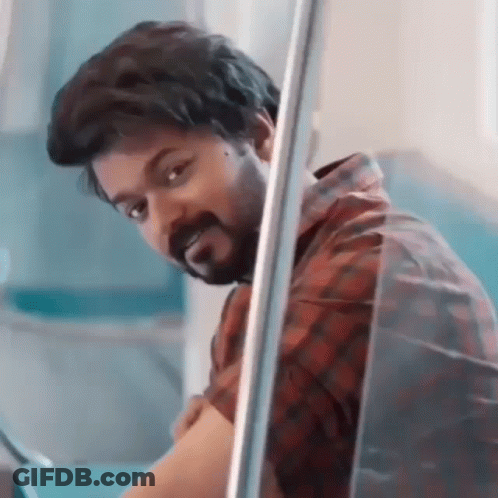 A Man With A Beard Is Peeking Out Of A Window And Looking At The Camera . GIF