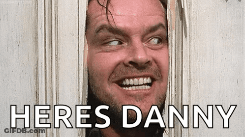 A Man With A Beard Is Peeking Through A Hole In A Door And Smiling . GIF