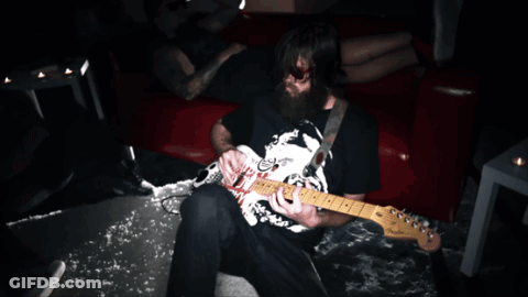 A Man With A Beard Is Playing A Guitar With A Sticker On It That Says ' Nirvana ' On It GIF