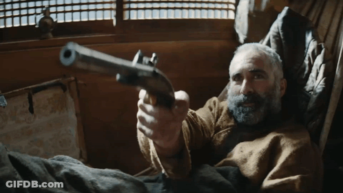 A Man With A Beard Is Pointing A Gun At The Camera GIF