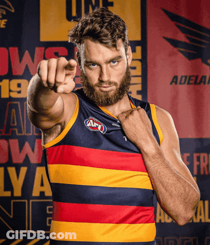 A Man With A Beard Is Pointing At The Camera In Front Of A Banner That Says Adelaide GIF
