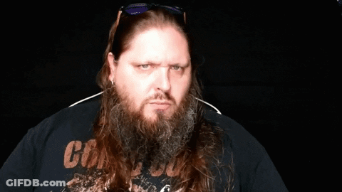 A Man With A Beard Is Pointing At The Camera While Wearing Sunglasses And A Watch . GIF