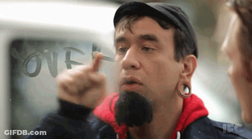 A Man With A Beard Is Pointing At The Word Over Written On A Window GIF