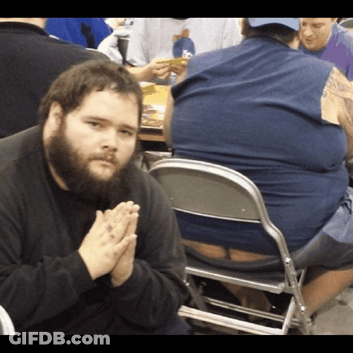 A Man With A Beard Is Praying While Sitting In A Chair GIF