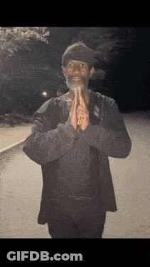 A Man With A Beard Is Praying With His Hands Folded In Front Of Him GIF