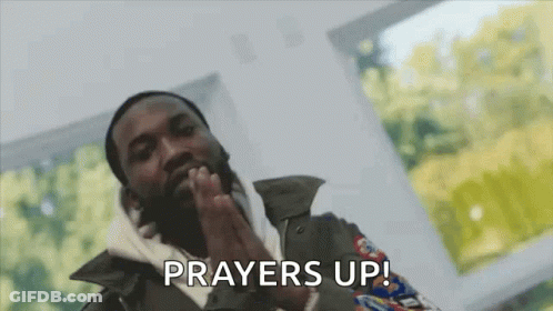 A Man With A Beard Is Praying With His Hands Folded In Front Of His Face . GIF
