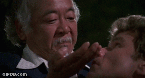 A Man With A Beard Is Putting Something In Another Man 'S Nose GIF