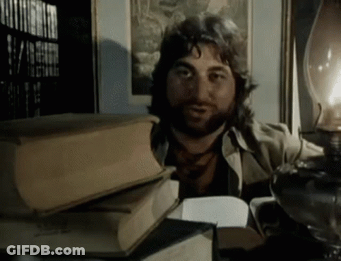 A Man With A Beard Is Reading A Book GIF