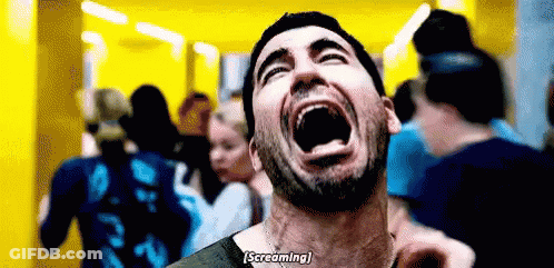A Man With A Beard Is Screaming With His Mouth Open In Front Of A Crowd . GIF