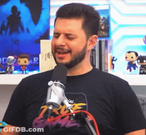 A Man With A Beard Is Singing Into A Microphone While Wearing A T-Shirt That Says 2K Game GIF