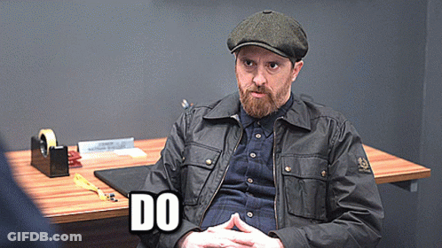 A Man With A Beard Is Sitting At A Desk With The Word Do Written On It GIF