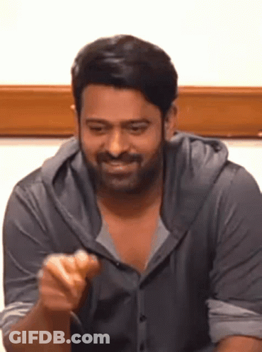A Man With A Beard Is Sitting At A Table And Eating A Sandwich . GIF