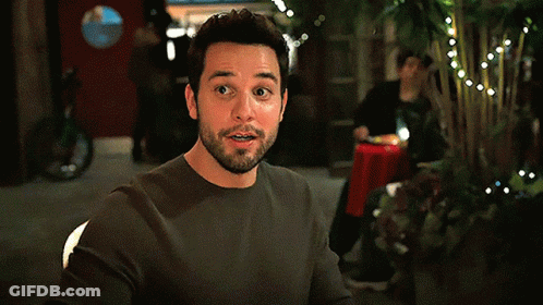 A Man With A Beard Is Sitting At A Table In A Dark Room GIF