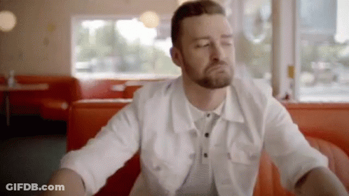 A Man With A Beard Is Sitting At A Table In A Diner . GIF