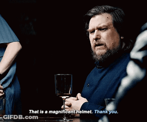 A Man With A Beard Is Sitting At A Table With A Glass Of Wine And Says That Is A Magnificent Helmet Thank You GIF