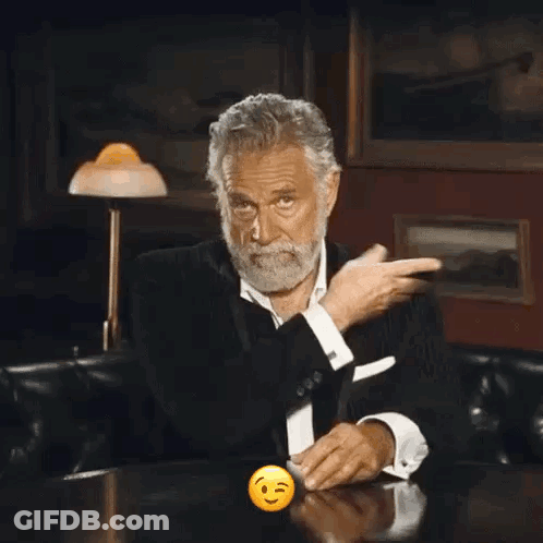 A Man With A Beard Is Sitting At A Table With A Smiley Face In Front Of Him GIF